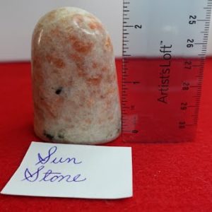 A piece of orange and white stone with ruler on red cloth