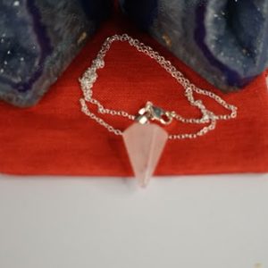 A pink crystal necklace sitting on top of a red table.