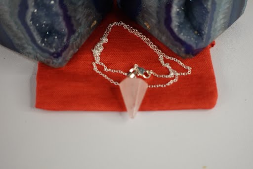A pink crystal necklace sitting on top of a red table.