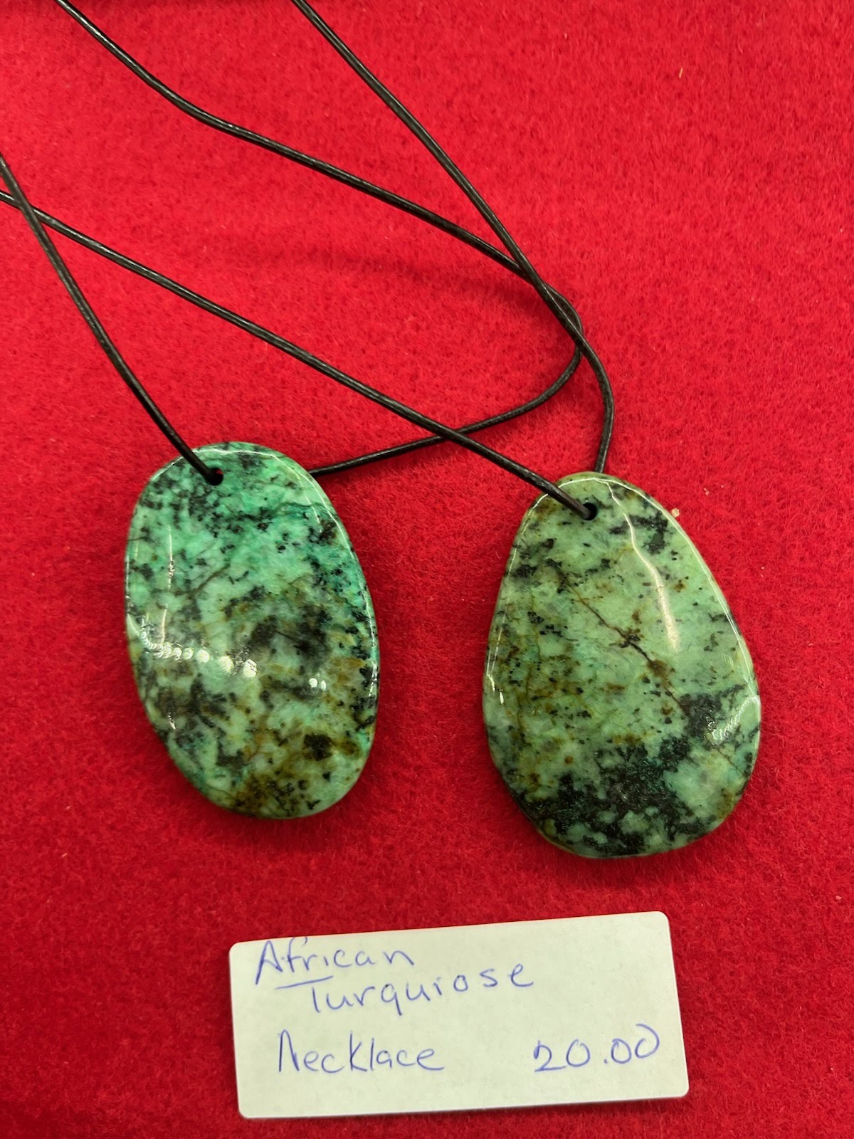 A pair of green stone pendants on a red surface