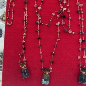 A red display case with three necklaces on it.