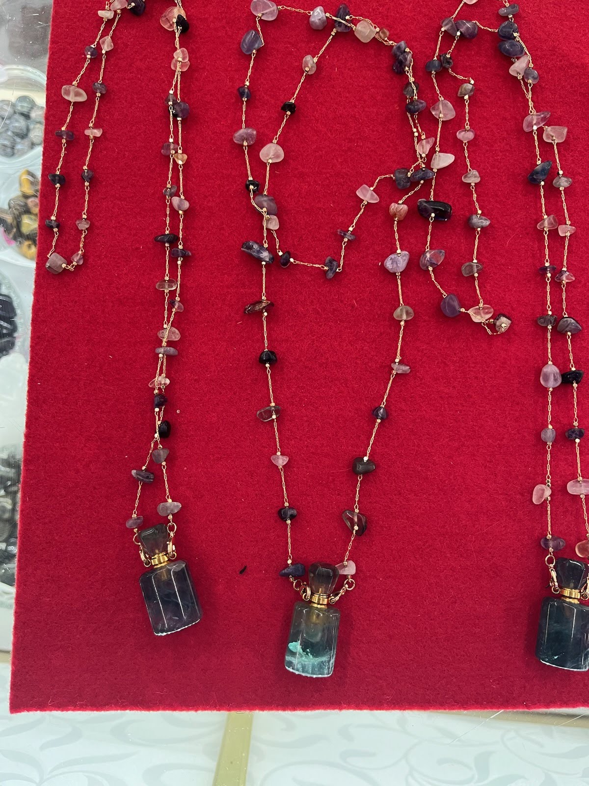 A red display case with three necklaces on it.