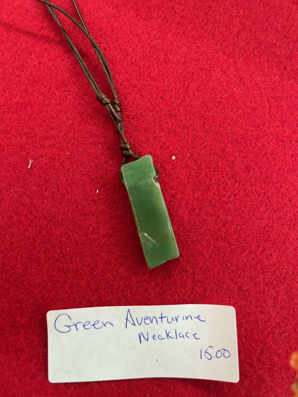 A green aventurine necklace is shown on a red background.