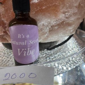 A bottle of lavender oil sitting next to a rock.