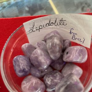 A bowl of purple and white rocks with a note on the side.