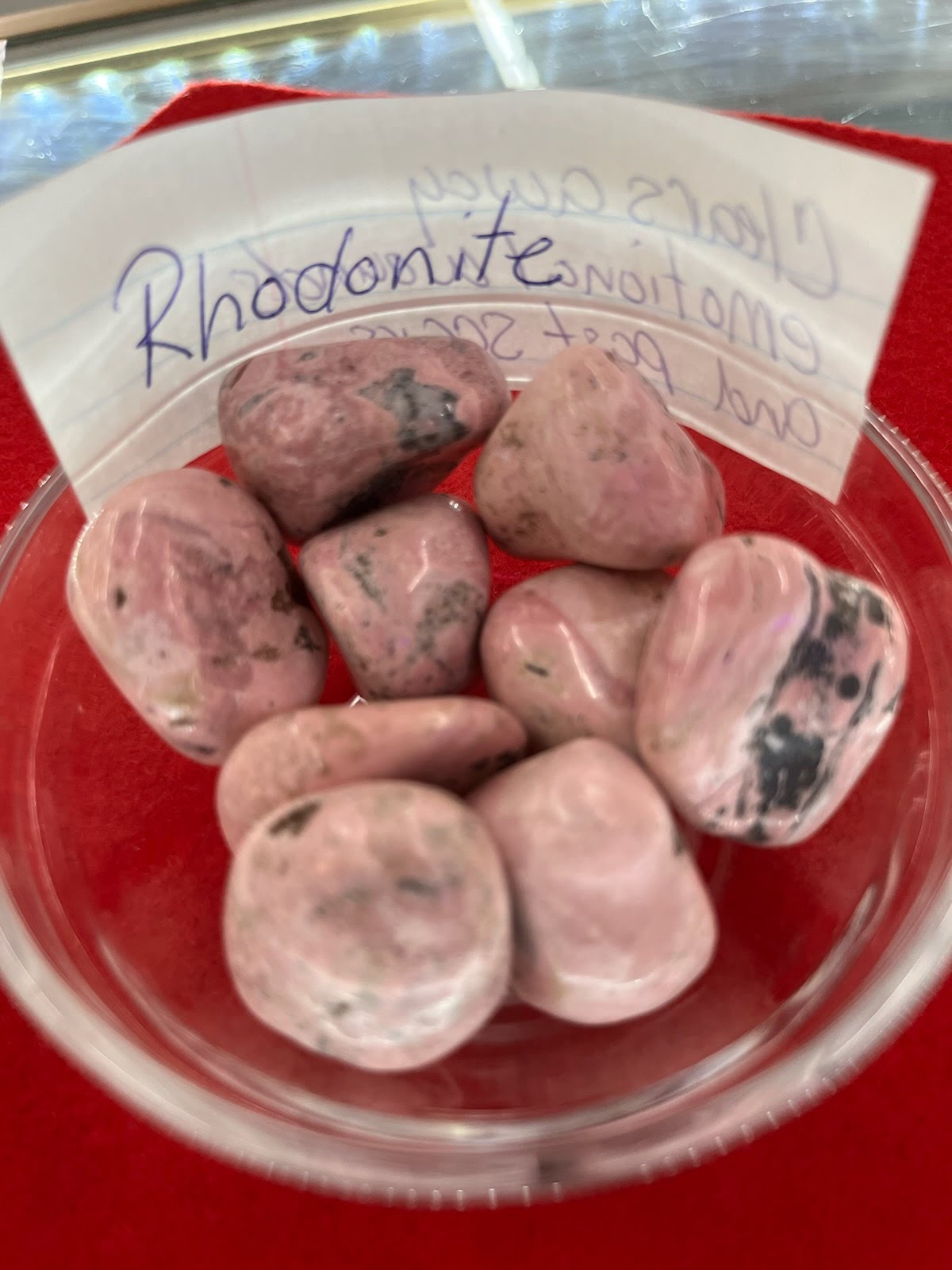 A bowl of rhodonite rocks with a note on the side.