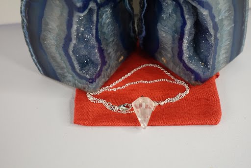 A necklace that is sitting on top of a red bag.