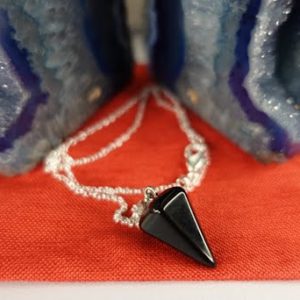 A black stone necklace sitting on top of a red table.