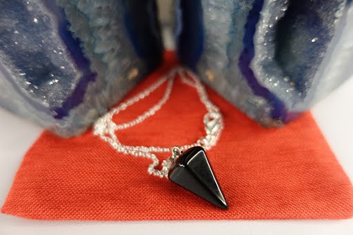 A black stone necklace sitting on top of a red table.