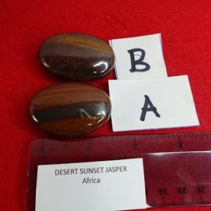 A red table with two brown stones and a ruler